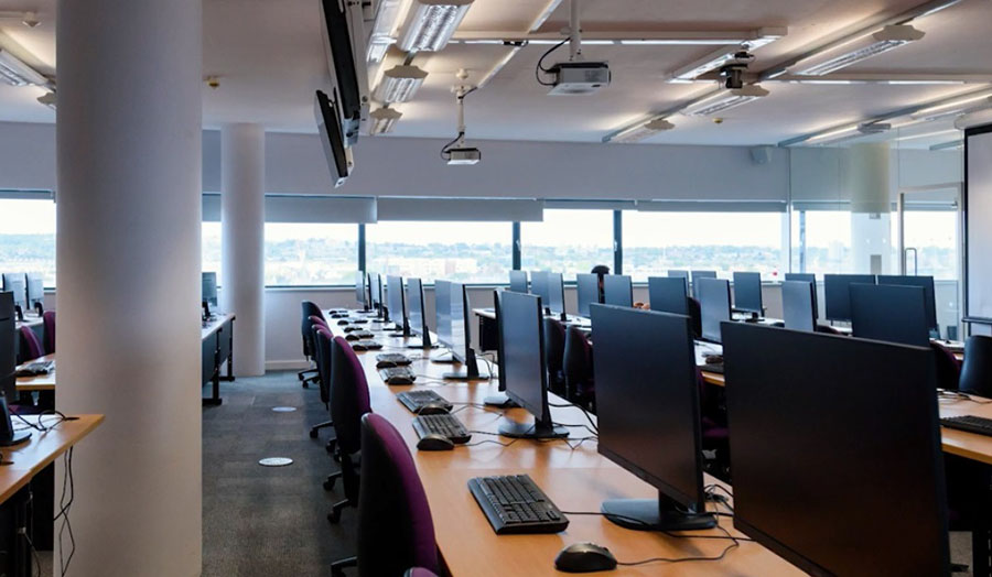 Cyber security lab showing rows of desks with computers and keyboards 