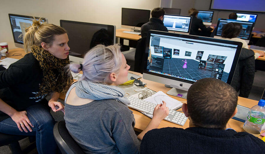 Three students in front of a Mac screen