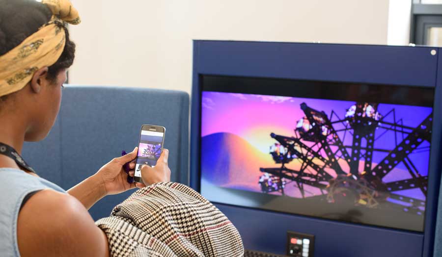 student taking a photo on her mobile phone of the screen in front of her