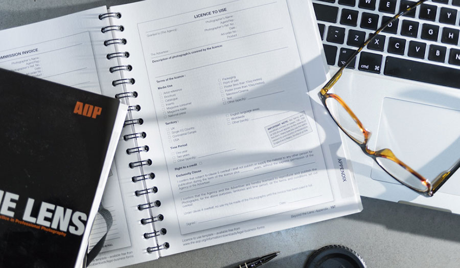 A desk with an open guidebook and a pair of reading glasses and a laptop keyboard
