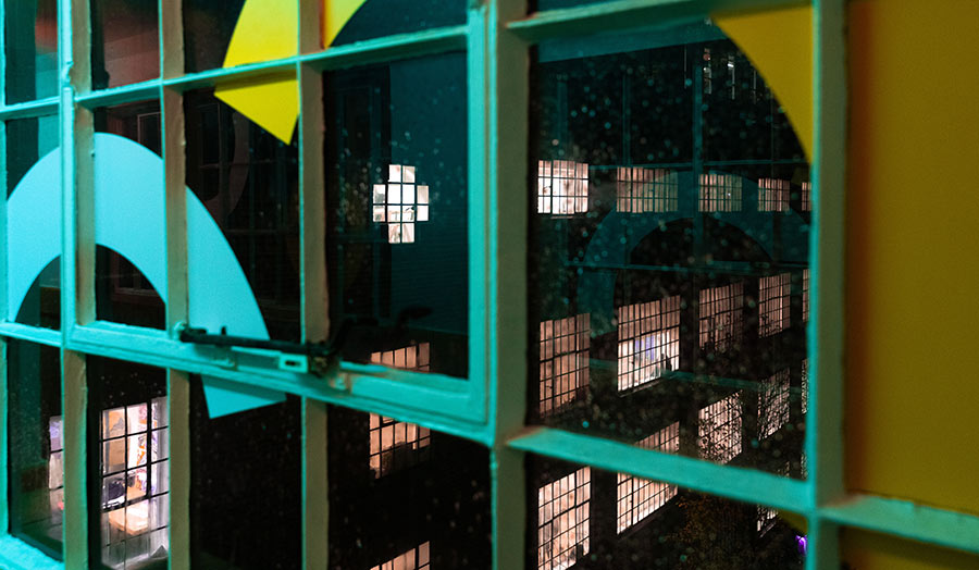 The view of the annex building at night through a window on the bridge over the street that connects the two buildings
