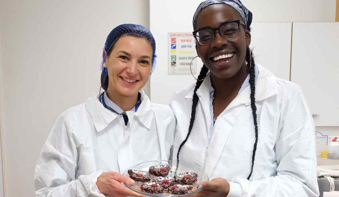 A pair of female students displaying their work to camera