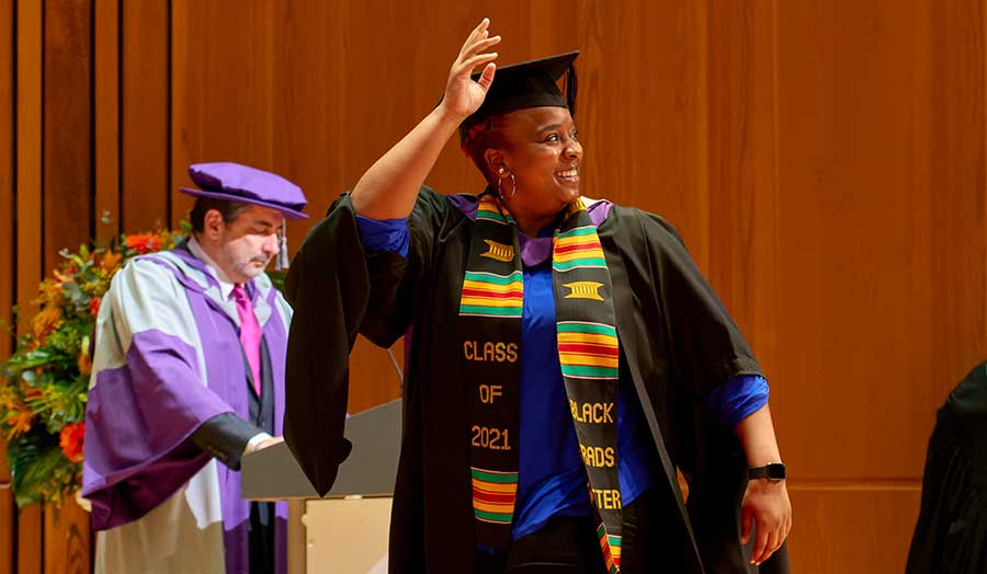 A Black London Met 2021 grad wearing a 'Black Grads Matter' scarf