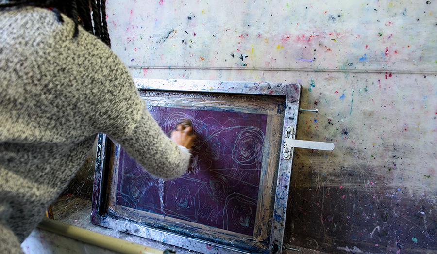 A woman scrubbing a textiles print plate clean