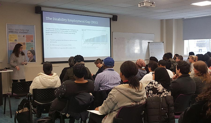 An audience is seated listening to a speaker