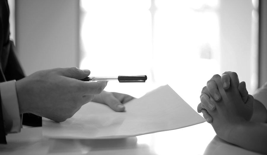 Hands giving a document and a pen to someone to sign