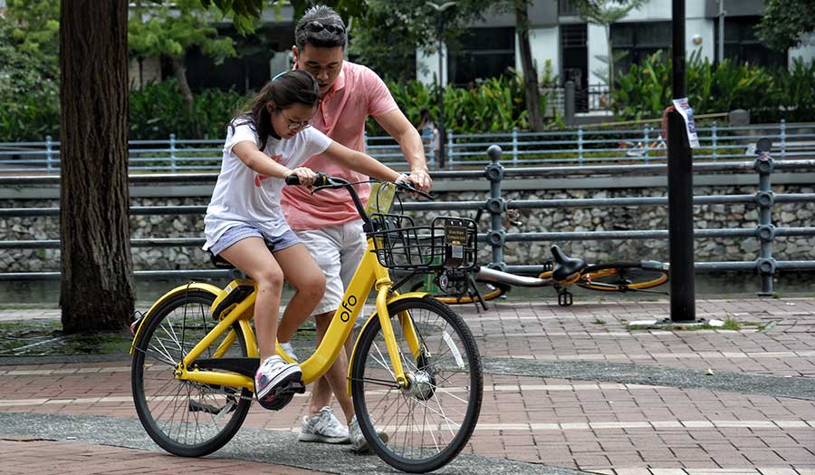 Father teaching daughter how to ride a bike