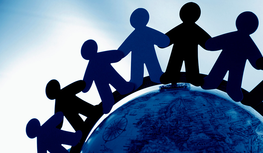 Paper figures hold hands around the globe