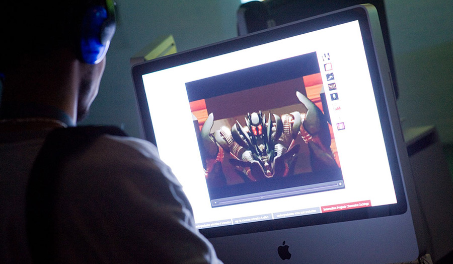 MA Digital Media - man wearing headphones sitting in front of a Mac