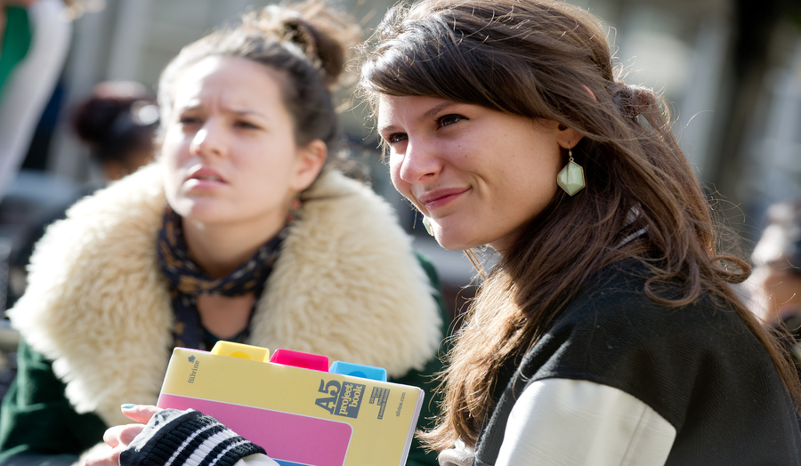 Two female students interacting with other people