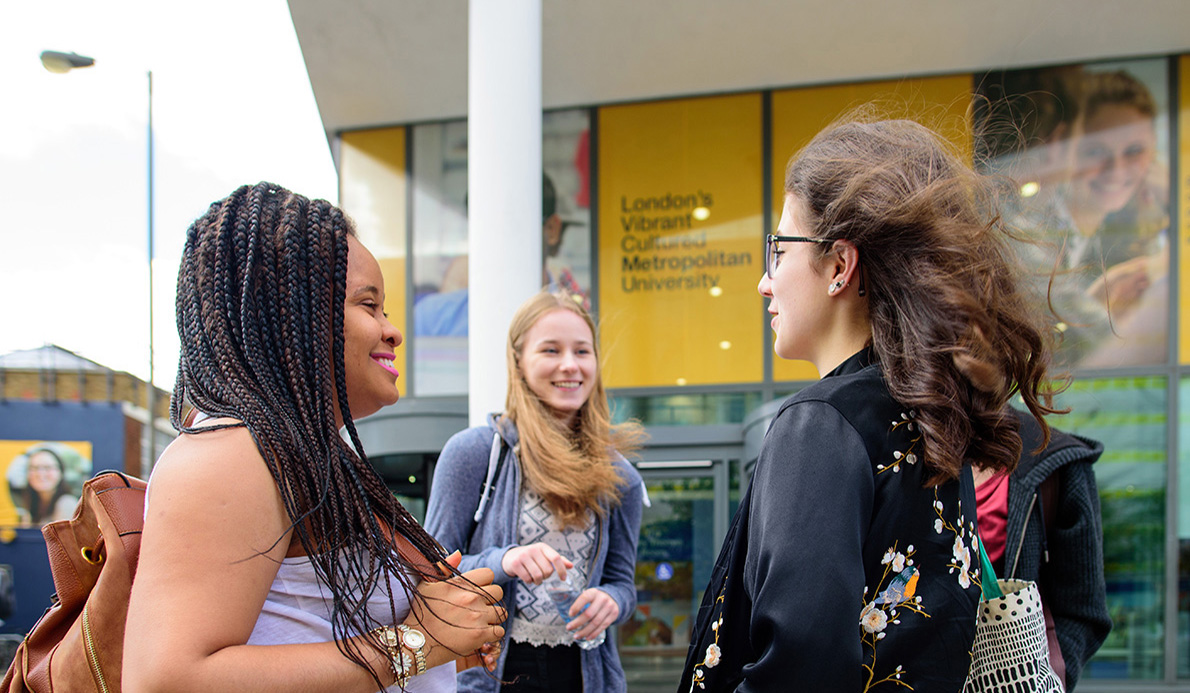 Female students smiling and talking outside Tower Building