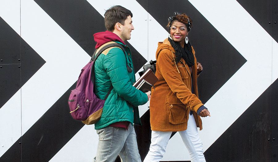 A male and female student outside a black and white building