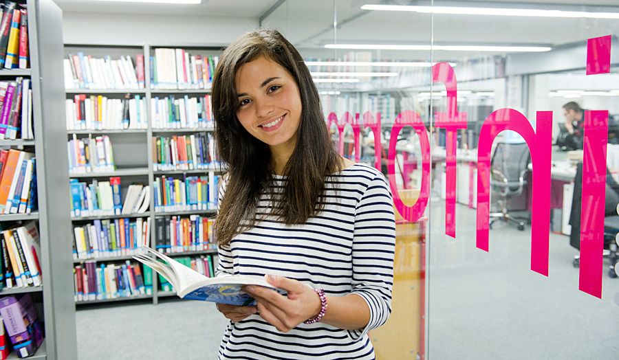 dark haired girl in the library with a book looking up